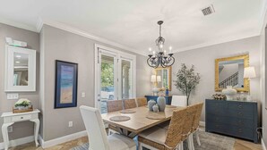 A dining area with a table, chairs, a chandelier, a mirror, and a dresser. - Coastal Chic Retreat | Pools | Tennis Court| Private Beach Access (Santa Rosa Beach)