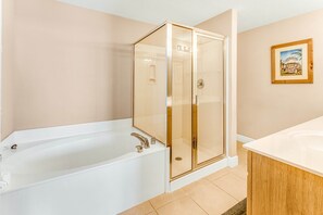 Un baño moderno con ducha envuelta en vidrio, bañera blanca y tocador de madera.