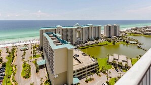 A hotel with multiple buildings, a parking area, and a view of the ocean. - Family-friendly beach condo with coastline views, balcony, shared pool, gym, tennis (Miramar Beach)