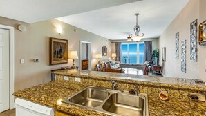 A kitchen with granite countertops, stainless steel sinks, and wooden cabinets. - Family-friendly beach condo with coastline views, balcony, shared pool, gym, tennis (Miramar Beach)