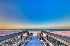 Un muelle de madera que conduce a una playa con cielo despejado.