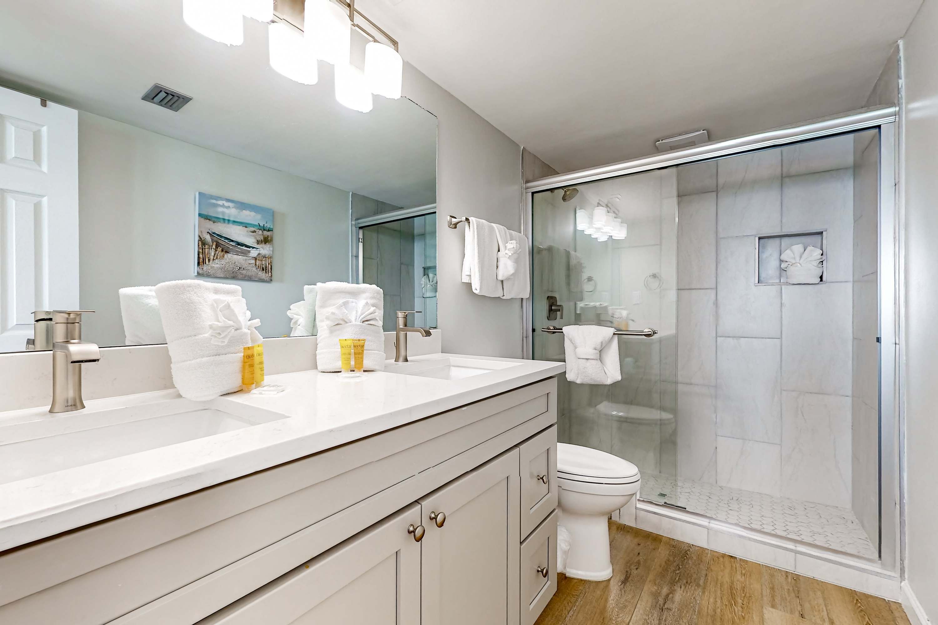 Un bagno moderno con uno specchio grande, due lavabi, un WC e una doccia vetrata.