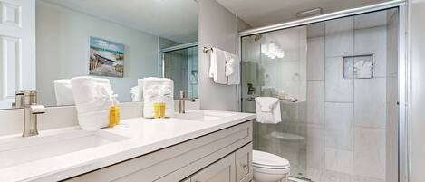 Un bagno moderno con uno specchio grande, due lavabi, un WC e una doccia vetrata.