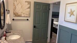 A bathroom with a sink, towel rack, and a door leading to a bedroom. - Waterfront Sunset Cove (Goobies)