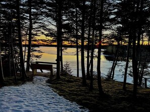 A bench overlooking a frozen lake with a forested backdrop. - Waterfront Sunset Cove (Goobies)