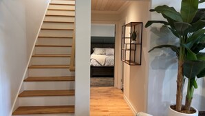 A staircase leading to a bedroom with a bed, a potted plant, and a wall-mounted shelf. - Waterfront Sunset Cove (Goobies)