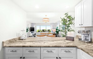 A modern kitchen with a marble countertop, white cabinets, and a dining area with a table and chairs. - Ground floor oceanfront beachy condo with furnished patio, outdoor pool, gym (Miramar Beach)