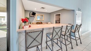 Een moderne keuken met een centraal eiland, barkrukken en feestdecoraties.