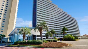 Un hotel moderno con fachada curva, varios pisos y un elemento vertical central.