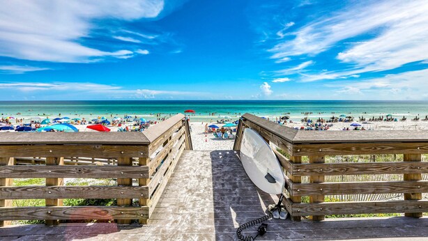 A wooden boardwalk leading to a beach with umbrellas and people. - Dog-friendly, Gulf-view home with pool, decks, WiFi, & WD - walk to beach (Santa Rosa Beach)