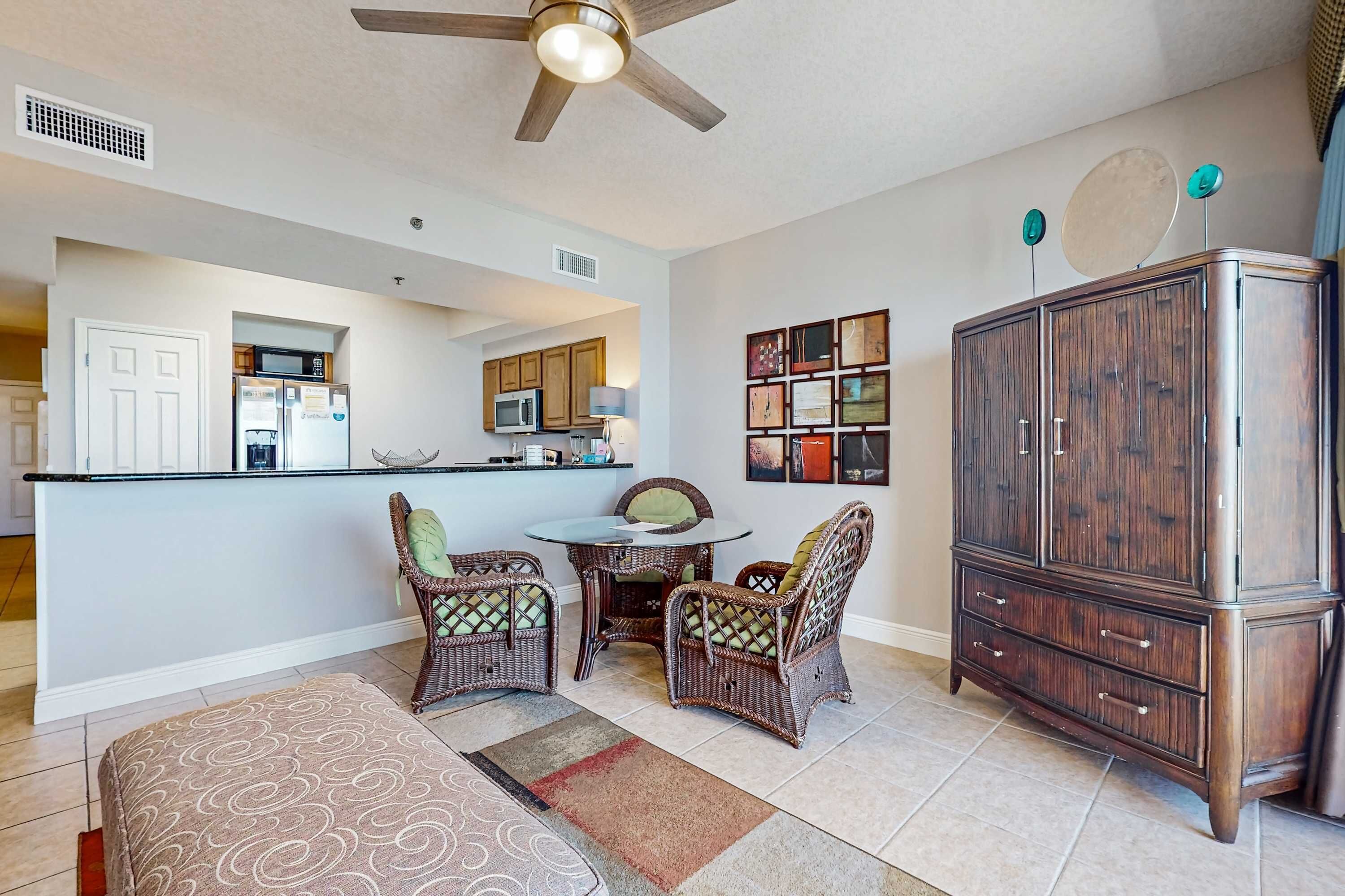 A living room with a sofa, two wicker chairs, a dining table, and a wooden cabinet.
