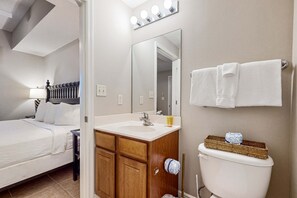 A bedroom with a bed, a wooden dresser, a white sink, and a toilet. - Gulf View Condo in Miramar Beach with Pool ,Gym and Beach Access (Miramar Beach)