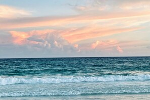 Une vue sur l’océan, avec des vagues et un ciel au coucher du soleil.