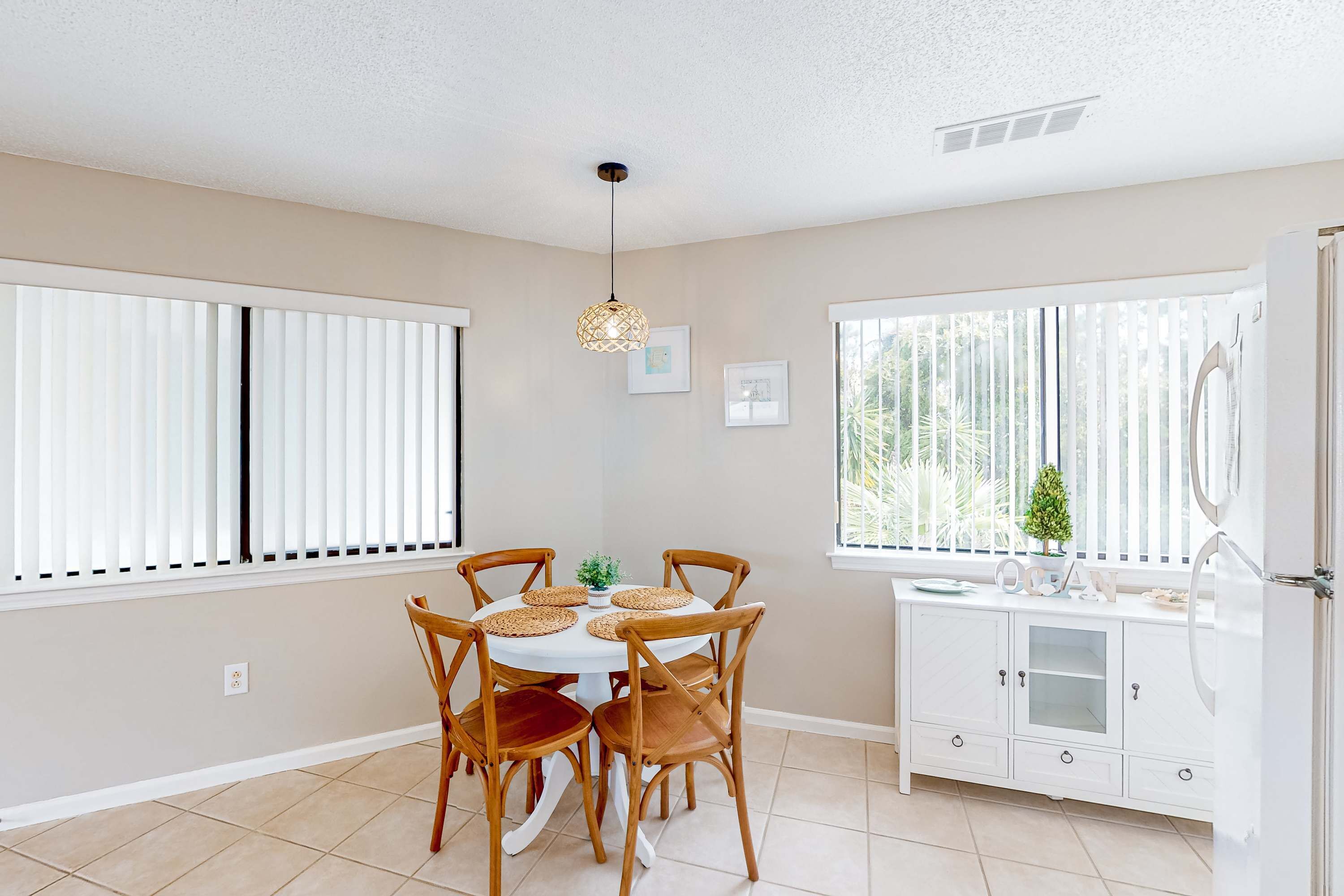 A dining area with a round table, six wooden chairs, and a hanging light fixture.