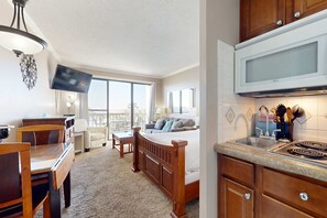 Een knus woongedeelte met een kitchenette, een eethoek en een slaapkamer.