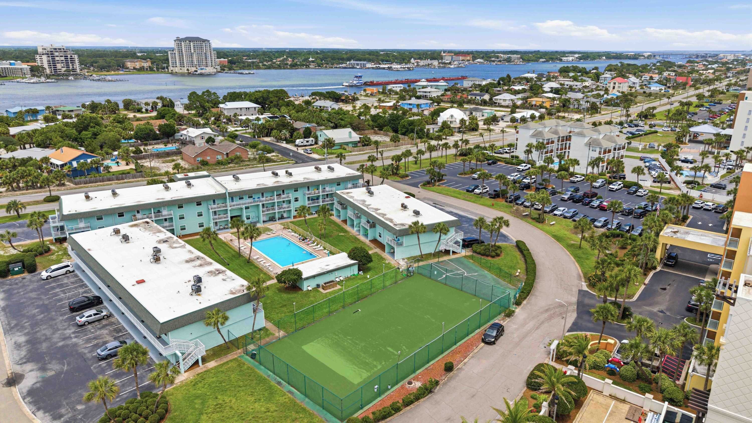 Ein Hotel mit Pool, Tennisplatz und Blick auf das Wasser.