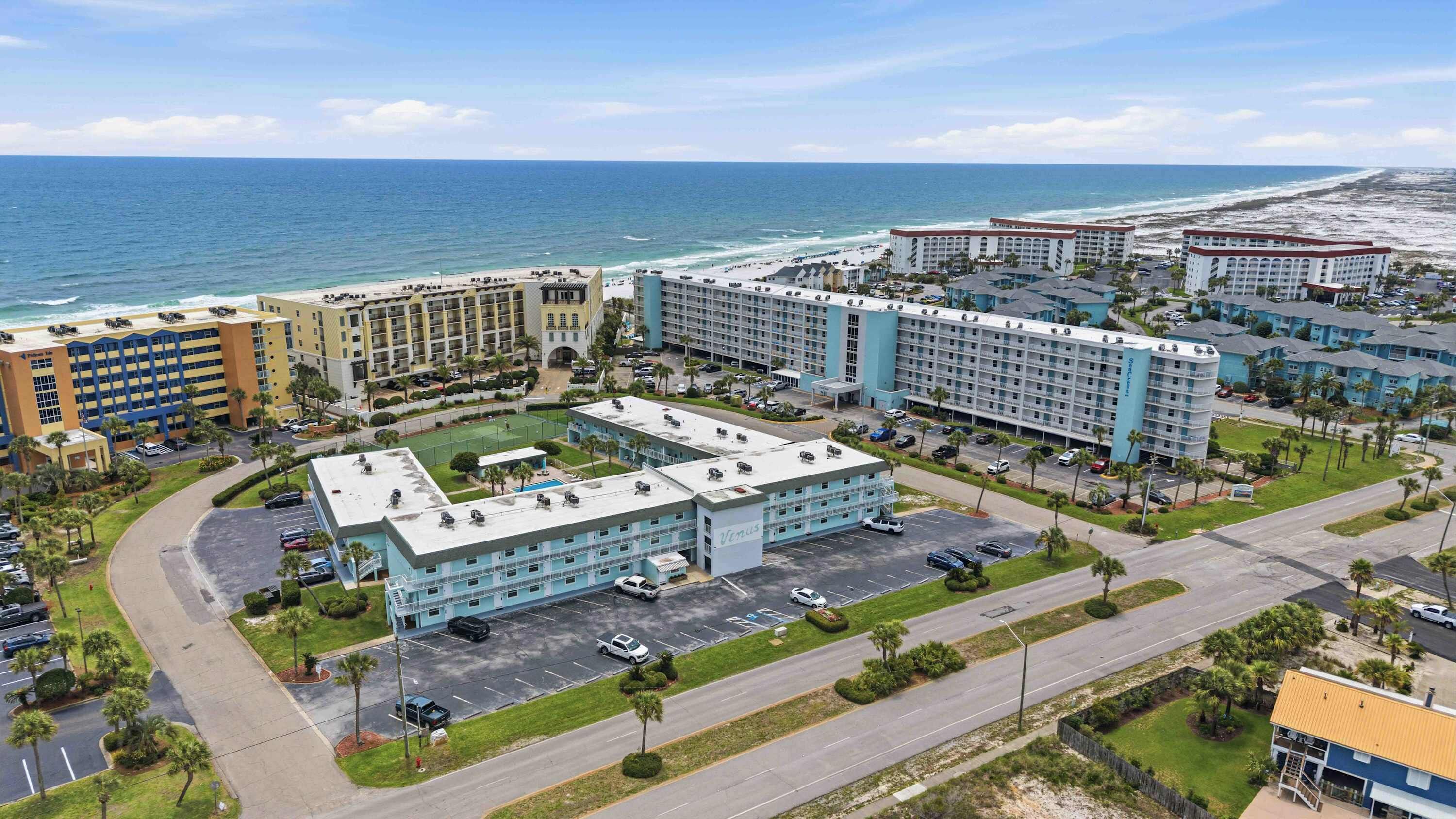 Een hotel met meerdere gebouwen, een parkeerplaats en uitzicht op het strand.