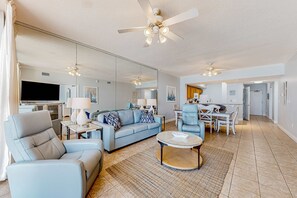 A spacious living room with a sofa, armchairs, a coffee table, and a dining area. - Beachfront condo with balcony, Gulf views, pools & fitness room (Fort Walton Beach)