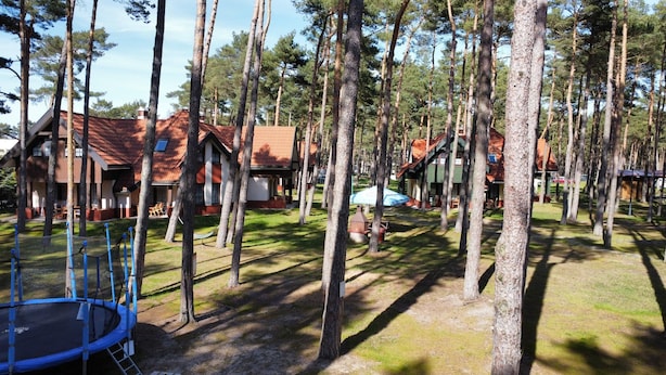 Un terrain de camping doté de plusieurs cabanes, d’un trampoline et d’un hamac.