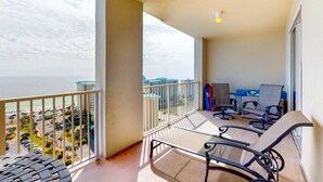 Un balcon avec vue sur l’océan, une table et deux chaises.