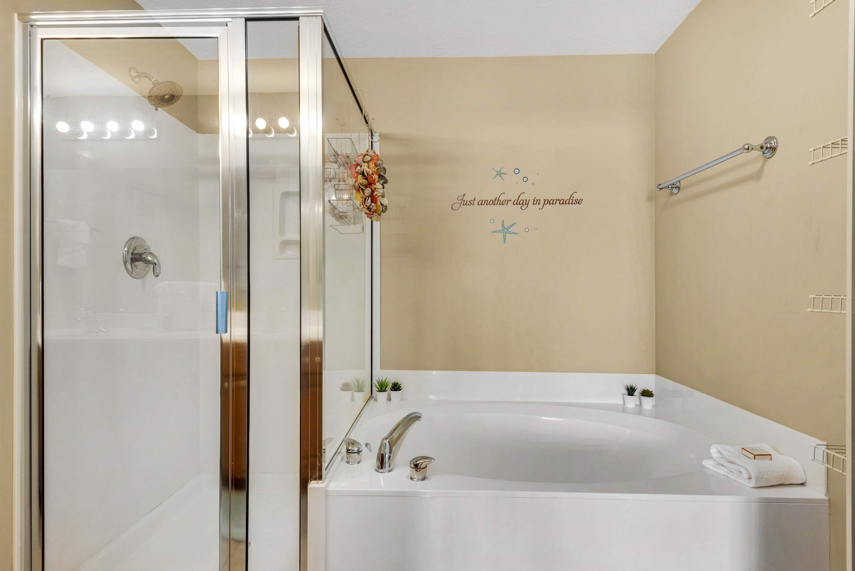 Un baño con ducha envuelta en vidrio, una bañera independiente y una pared decorativa con una estrella de mar y texto.