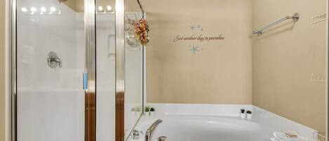Un baño con ducha envuelta en vidrio, una bañera independiente y una pared decorativa con una estrella de mar y texto.