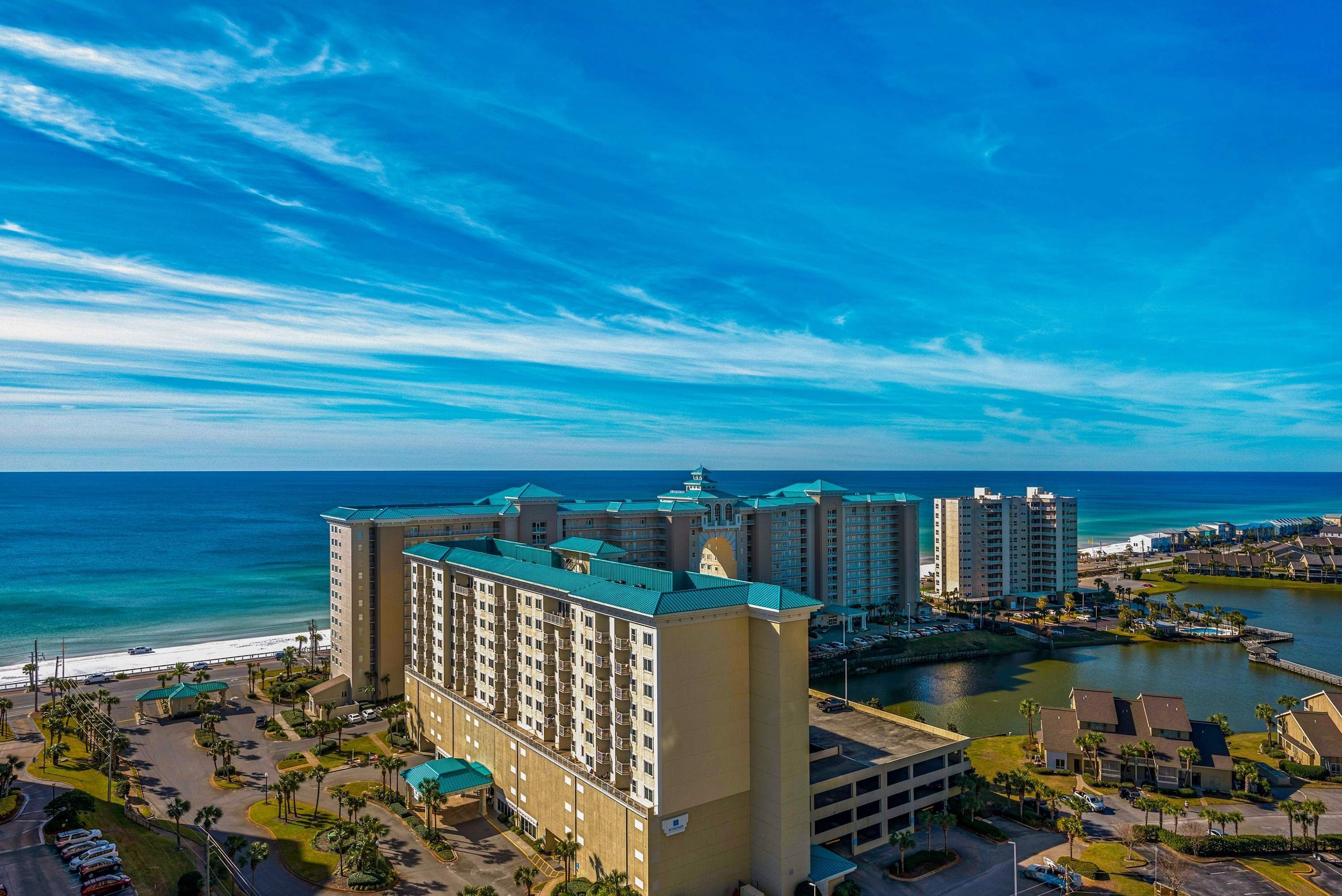 A hotel with multiple buildings, a parking area, and a view of the ocean.