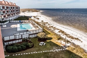 A hotel with a pool, a beach view, and a fenced garden area. - Inviting condo with bay & ocean views, & pool - steps to the beach (Pensacola Beach)