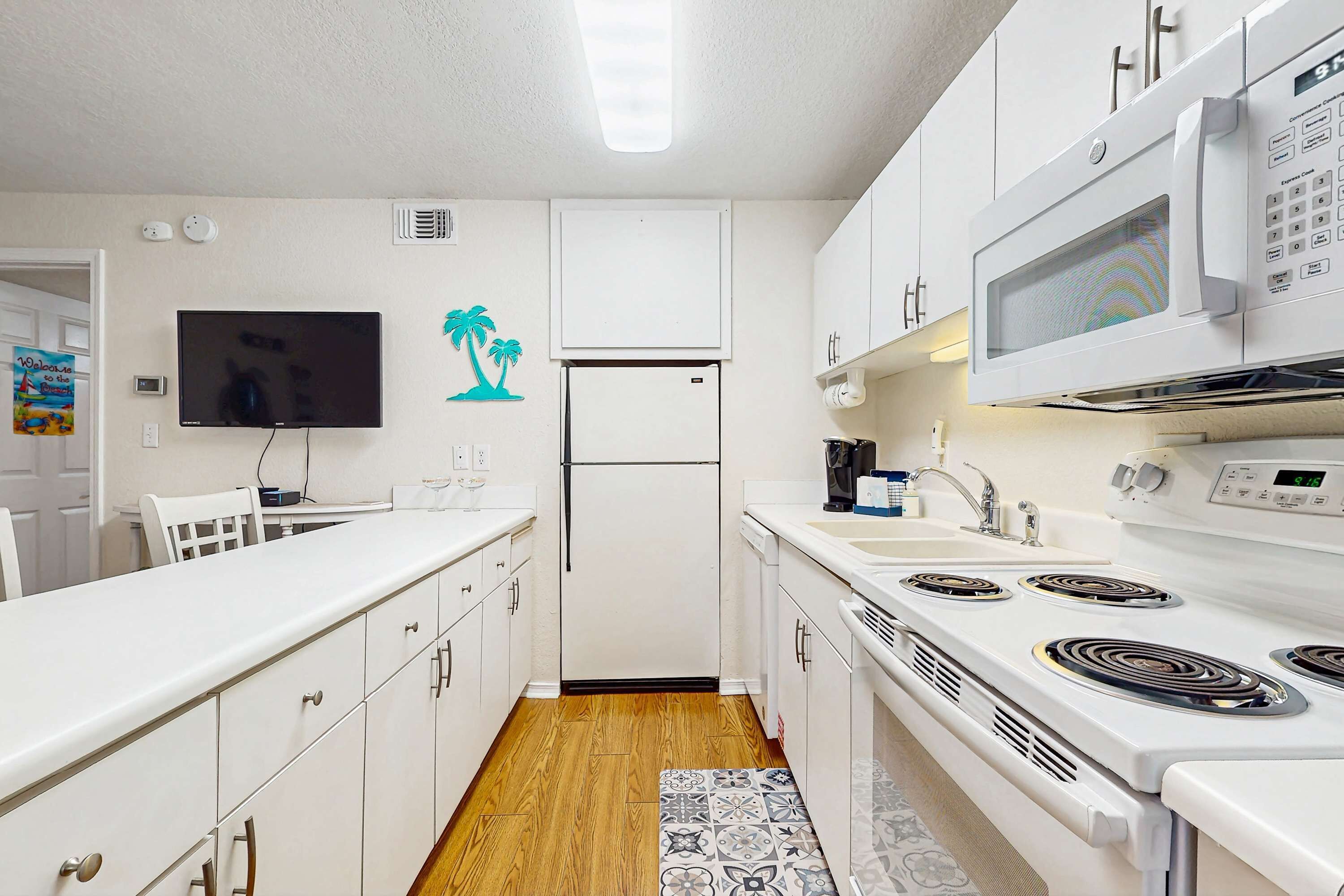 A modern kitchen with white cabinets, a microwave, a refrigerator, and a stove.