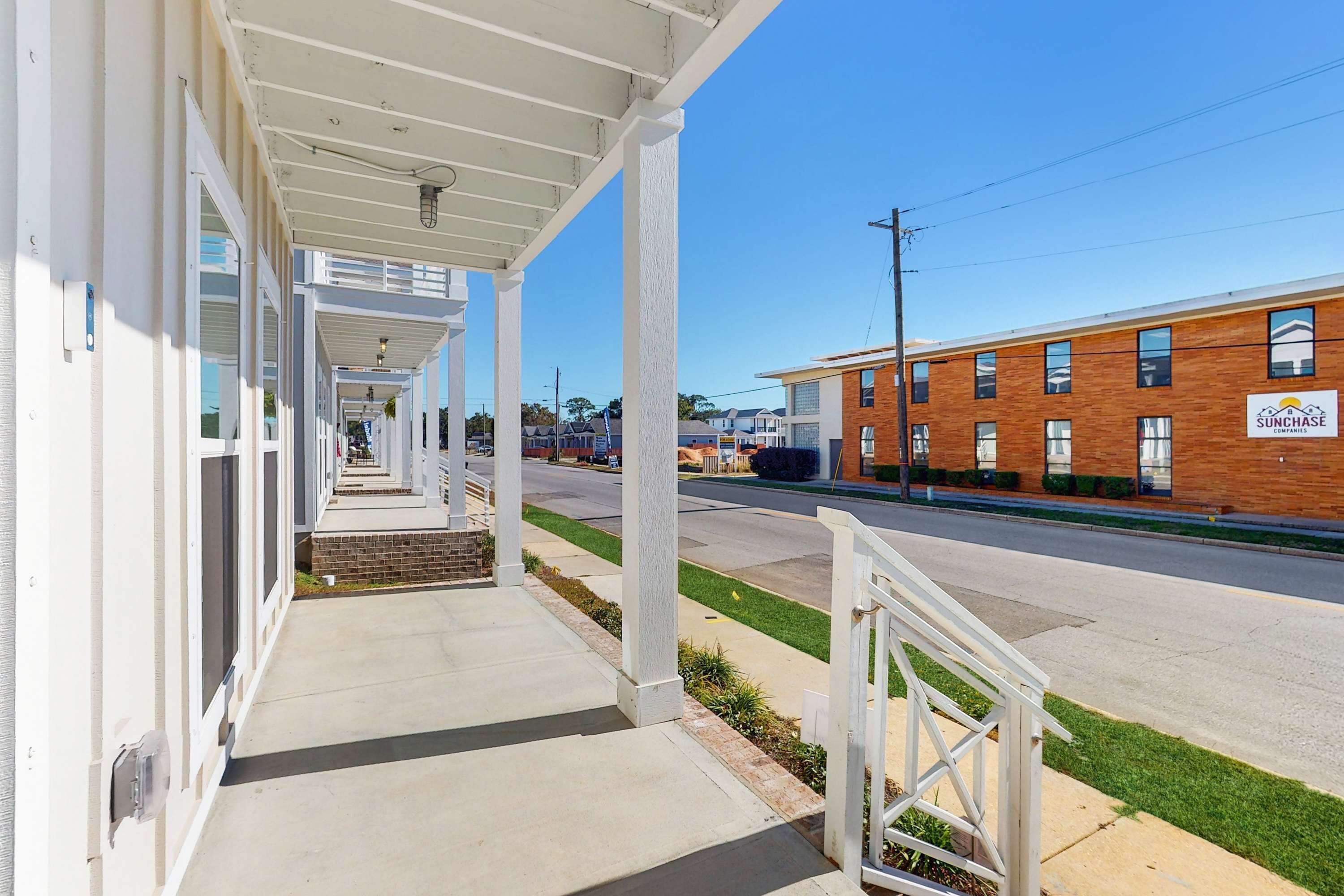 A covered outdoor area with a sidewalk leading to a building with a brick facade and a sign for 'Sunchase.'