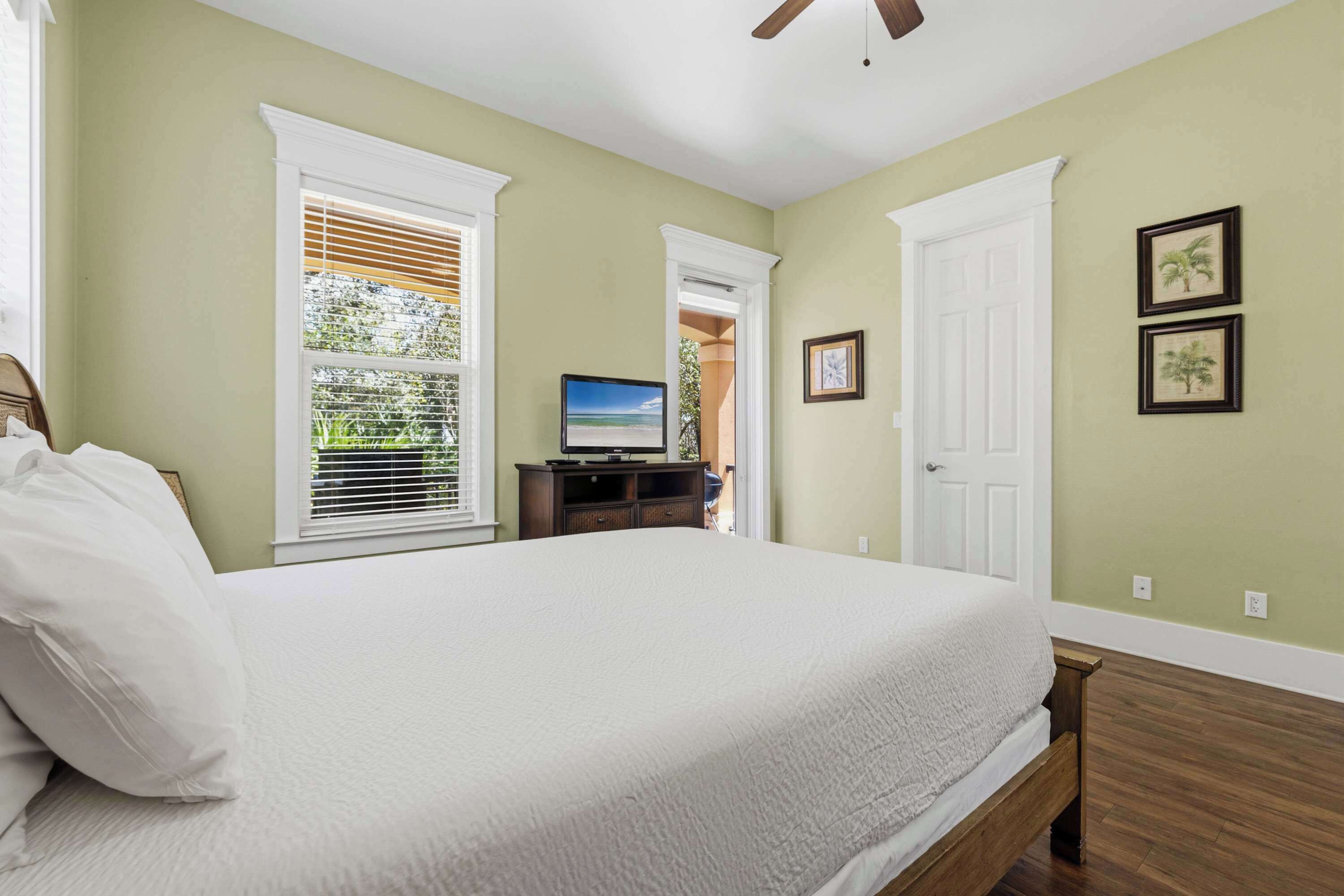 A bedroom with a bed, a TV, a dresser, and two framed pictures on the wall.