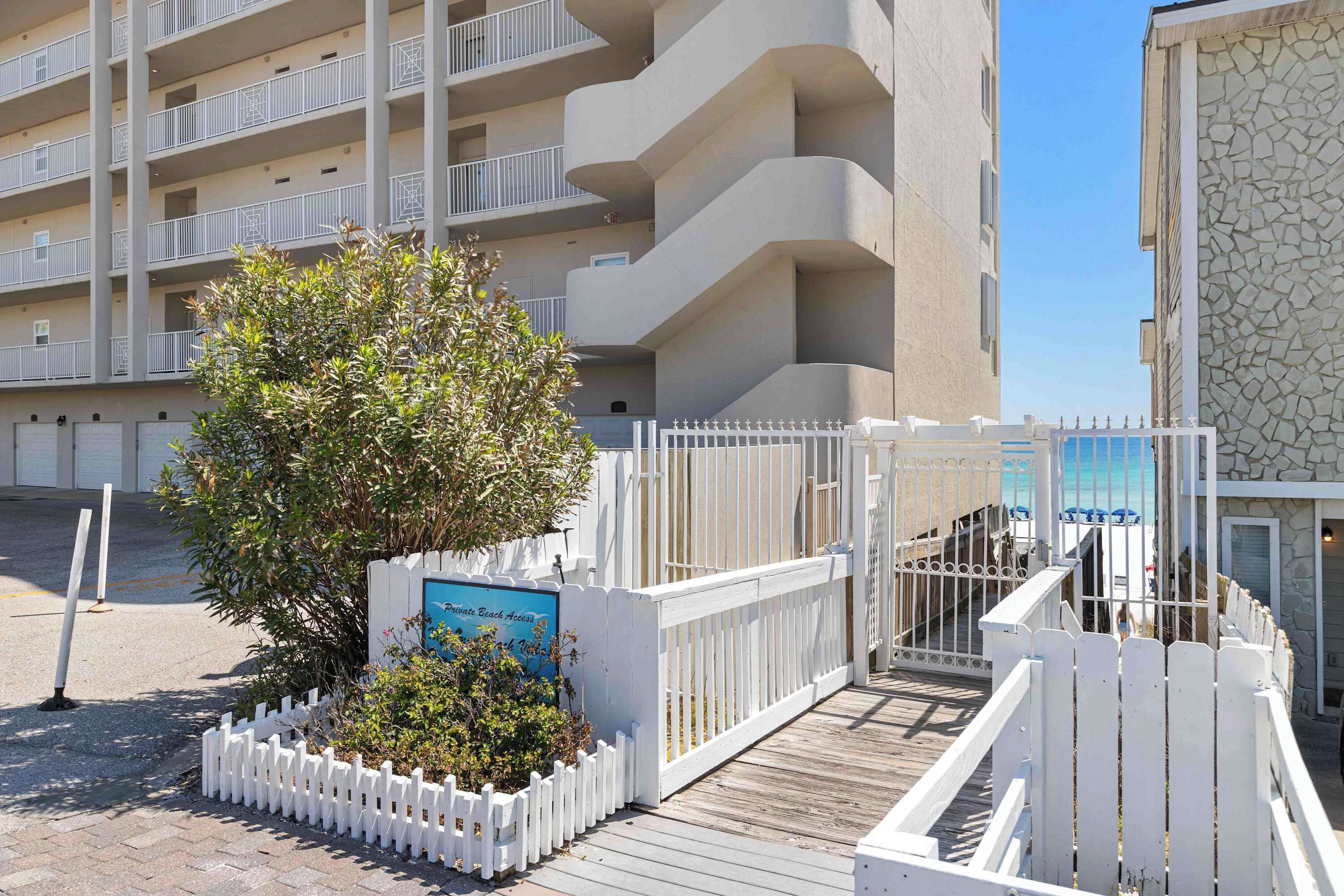 A multi-story hotel with balconies, a wooden deck, and a white picket fence.