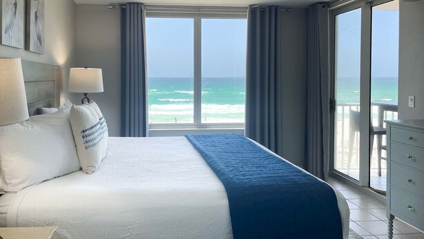 Une chambre d’hôtel avec un grand lit, une vue sur l’océan et un balcon.