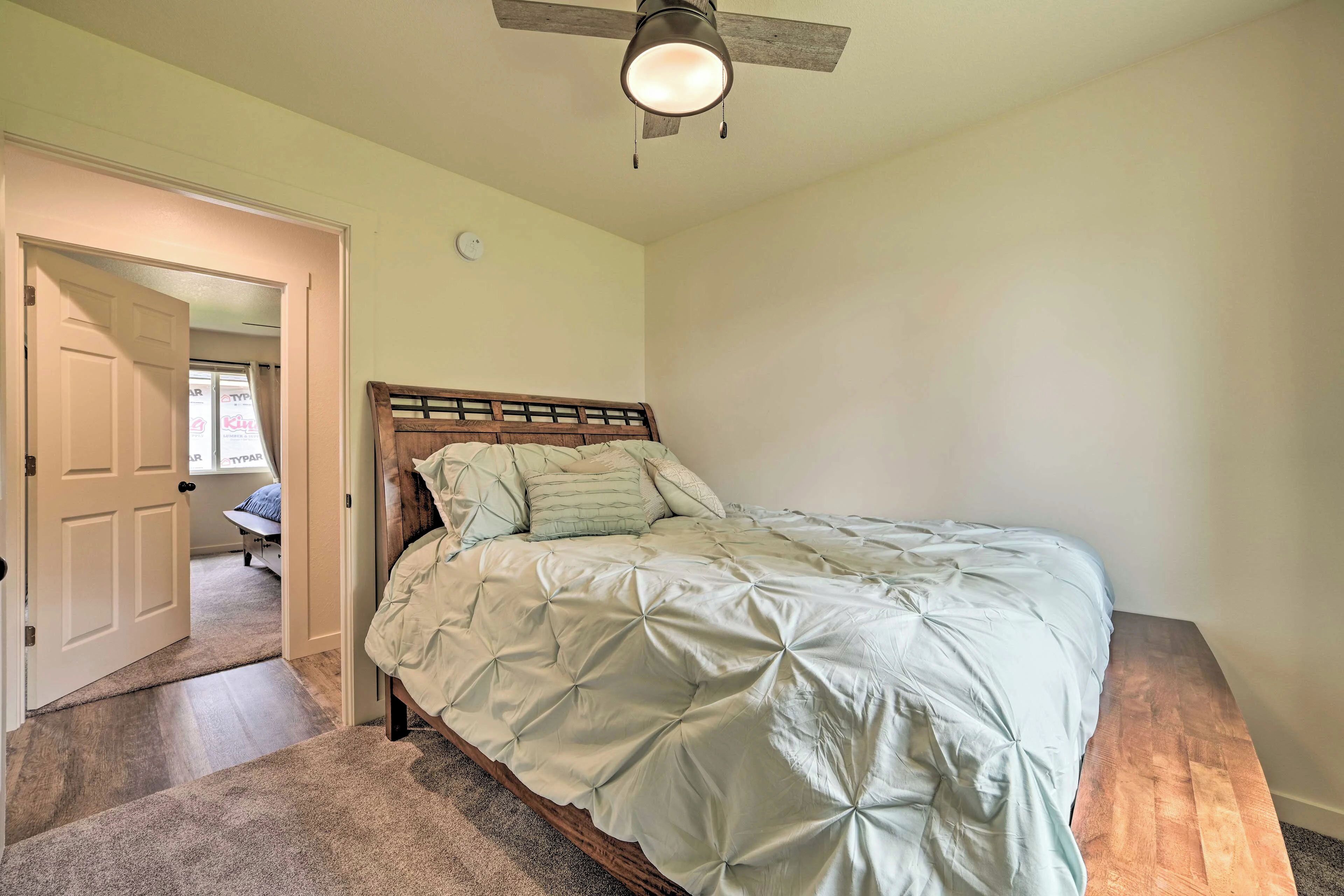 A bedroom with a bed, a ceiling fan, and a door leading to another room.