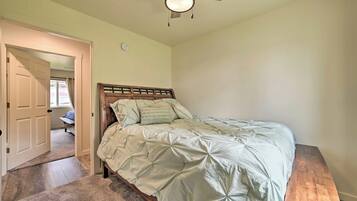 A bedroom with a bed, a ceiling fan, and a door leading to another room.