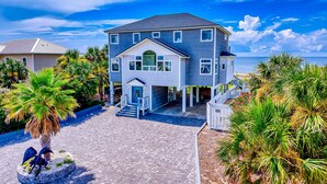 A two-story house with a front porch, a staircase, and a view of the ocean. - Gulf-front home with direct beach access, Gulf views, yard, & deck (St. George Island)
