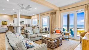 A spacious living area with a sofa, coffee table, and a view of the beach through large sliding doors. - Gulf-front home with direct beach access, Gulf views, yard, & deck (St. George Island)