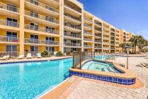 Un hôtel doté d’une grande piscine, de nombreux balcons et offrant une vue sur un ciel d’un bleu éclatant.