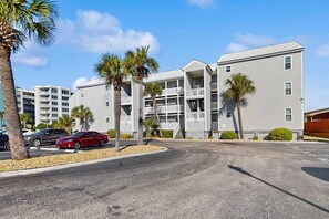 A multi-story hotel with balconies, palm trees, and a parking lot. - Hermitage 313 - Beautiful Soundfront Condo with Free WiFi, Sound Views, AC, W&D, & Shared Pool (Fort Walton Beach)