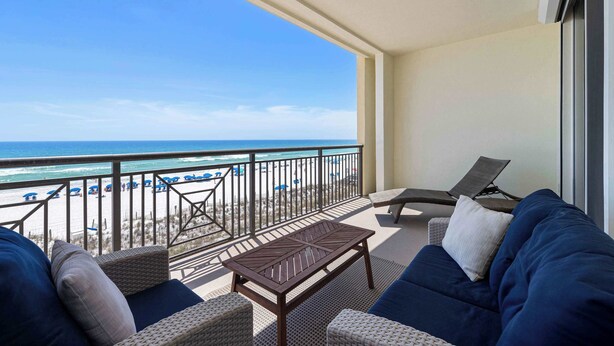 Een balkon met uitzicht op het strand, een lounge stoel, een bank en een bijzettafeltje.