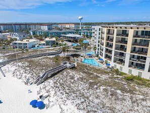 Un hôtel situé sur la côte, composé de plusieurs bâtiments, doté d’une piscine et d’une plage avec une promenade en bois.