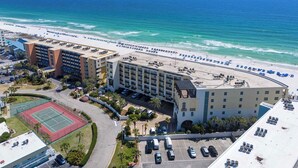 Een hotel met een tennisbaan, parkeergelegenheid en uitzicht op het strand.