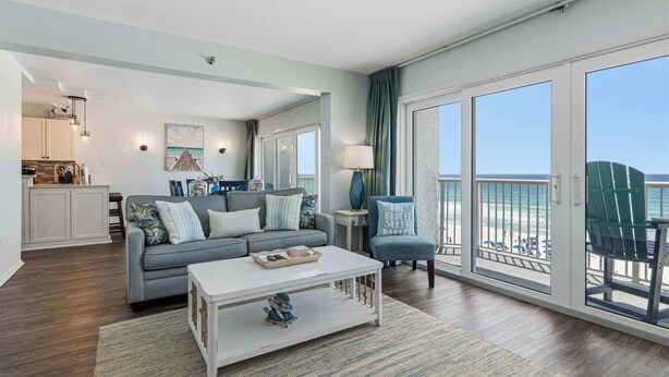 Ein Wohnzimmer mit einer Couch, einem Couchtisch und Blick auf den Strand durch große Schiebetüren.