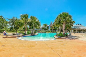 A swimming pool surrounded by palm trees and a children's play area. - Lovely coastal home with pool access, fast WiFi, screened patio & great location (Port St. Joe)