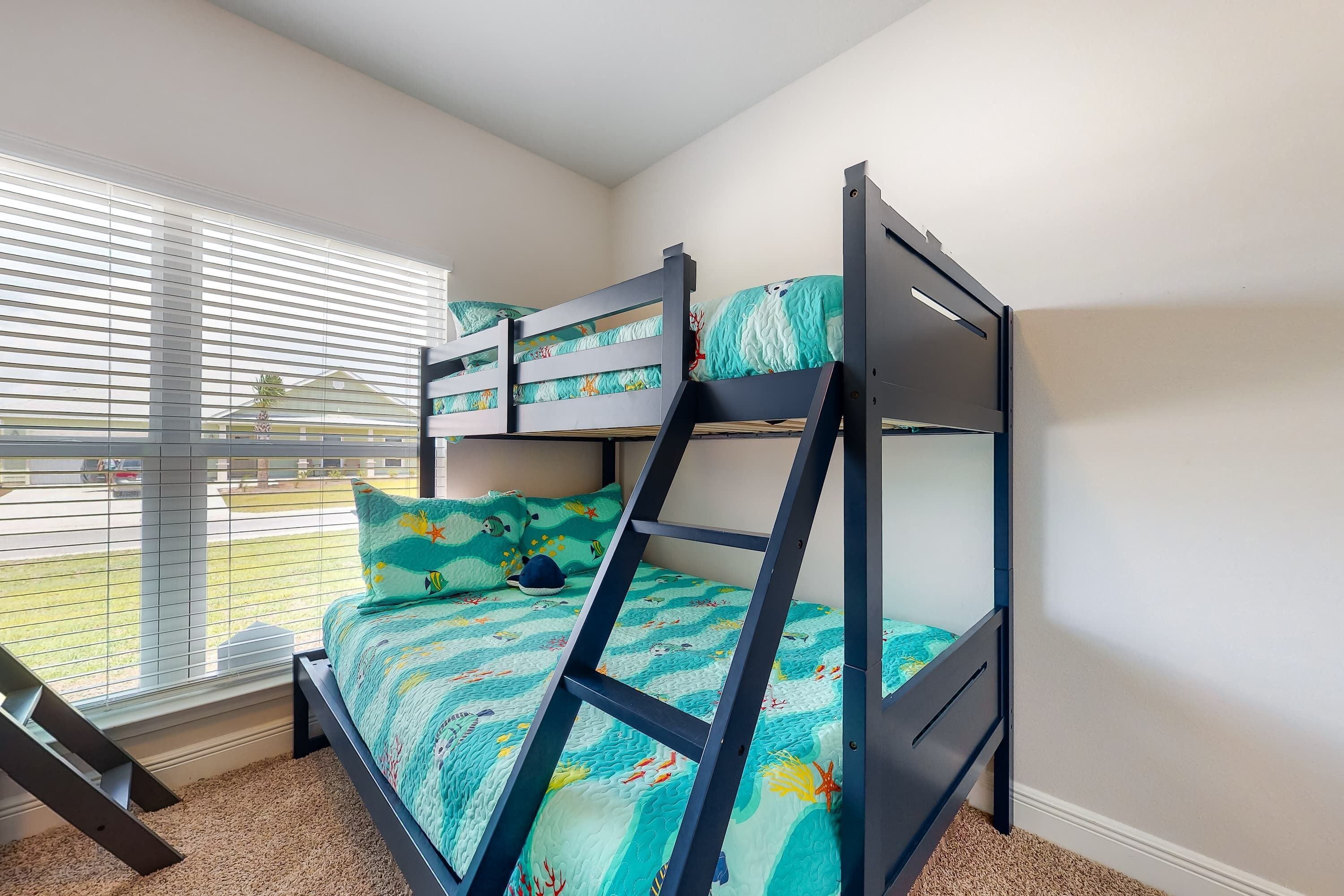 A bunk bed with a blue frame and a green bedspread with a sea-themed design.