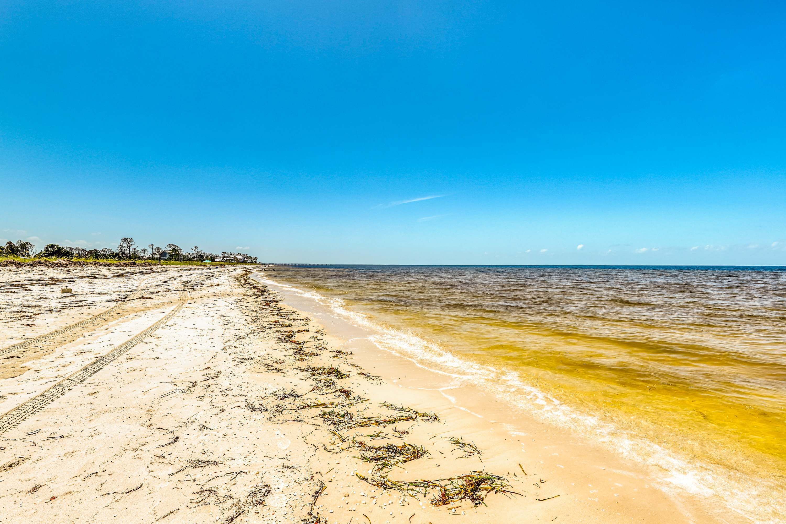 Una playa arenosa con agua cristalina y cielo despejado.