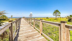 A wooden boardwalk leading to a beach with a clear sky. - Lovely coastal home with pool access, fast WiFi, screened patio & great location (Port St. Joe)