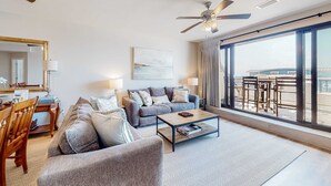 A modern living room with a sofa, coffee table, and dining area. - Renovated oceanfront condo with lanai, pool, hot tub & view - snowbird-friendly (Mexico Beach)