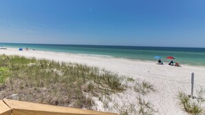A beach with clear skies, a sandy shore, and a few people and umbrellas. - Renovated oceanfront condo with lanai, pool, hot tub & view - snowbird-friendly (Mexico Beach)