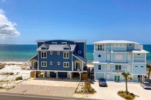 Een hotel aan het strand met gebouwen van twee verdiepingen, een overdekte parkeerplaats en uitzicht op de oceaan.